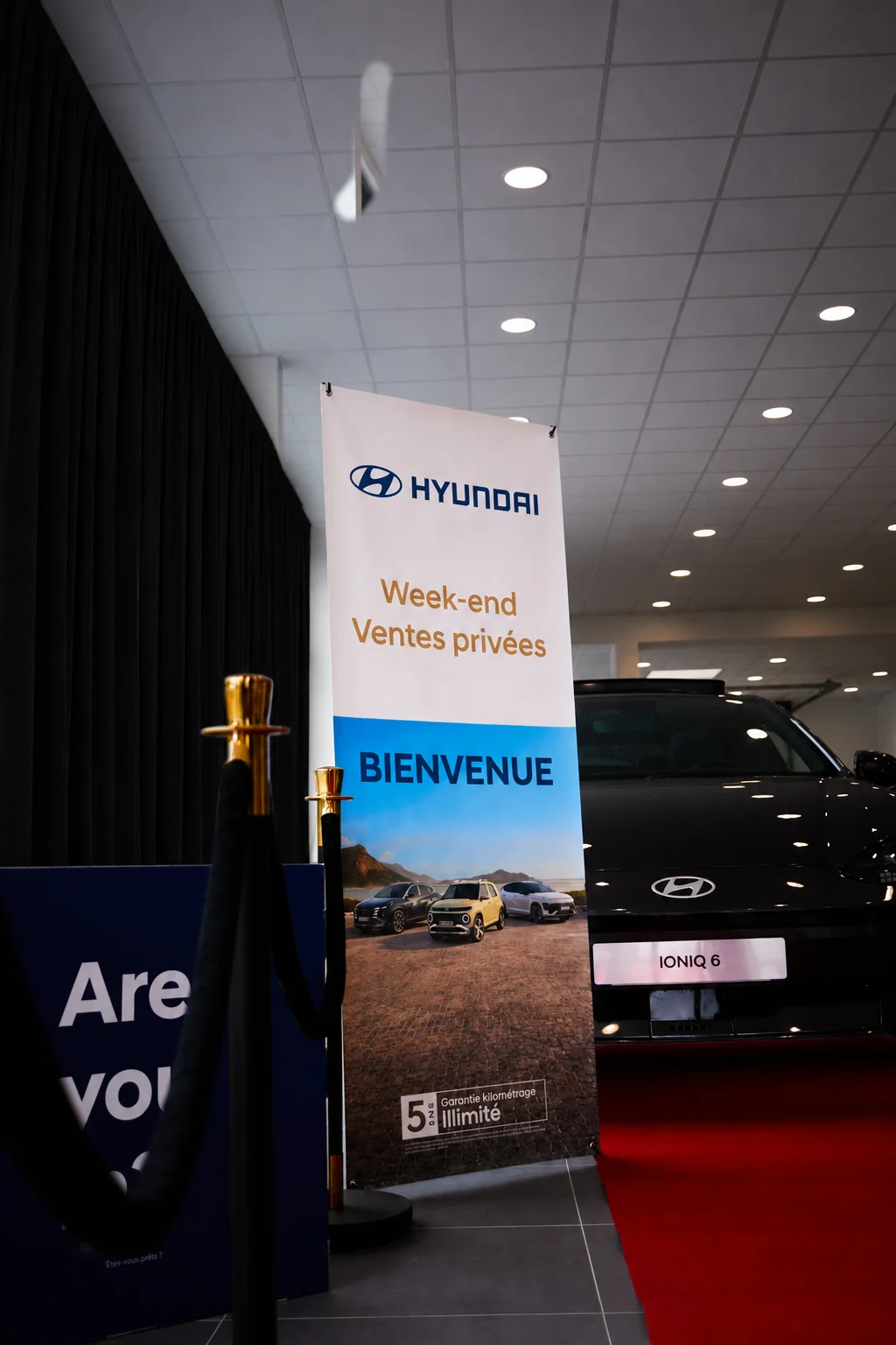 Vente privée automobile avec signalétique, rideaux noirs et tapis rouge